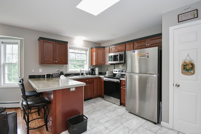 31 Bristol St, Thomaston, CT 06787 - kitchen featuring stainless steel appliances, tile countertops, a peninsula, a breakfast bar, and baseboard heating