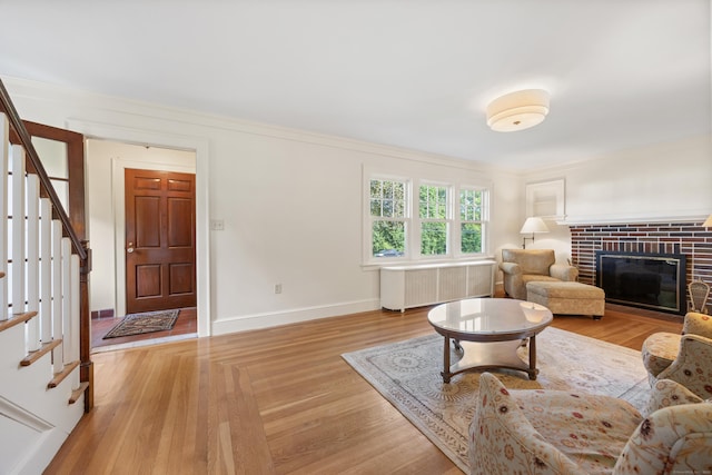 22 Spring Rd, North Haven, CT 06473 - living area featuring radiator, stairs, light wood-style flooring, a brick fireplace, and crown molding