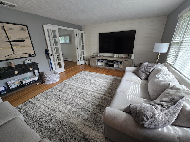 77 Hartz Ln, East Hartford, CT 06118 - living area with french doors, healthy amount of natural light, wood finished floors, a textured ceiling, and wood walls