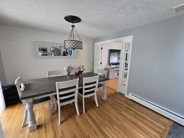77 Hartz Ln, East Hartford, CT 06118 - dining room with a baseboard radiator, light wood-type flooring, and a textured ceiling