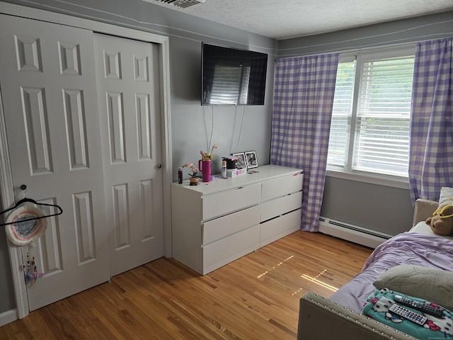 77 Hartz Ln, East Hartford, CT 06118 - bedroom featuring a baseboard radiator, light wood-style floors, and a textured ceiling