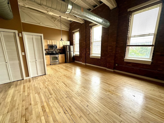 325 Lafayette St Unit 3303, Bridgeport, CT 06604 - unfurnished living room with light wood-style floors, plenty of natural light, brick wall, beamed ceiling, and high vaulted ceiling
