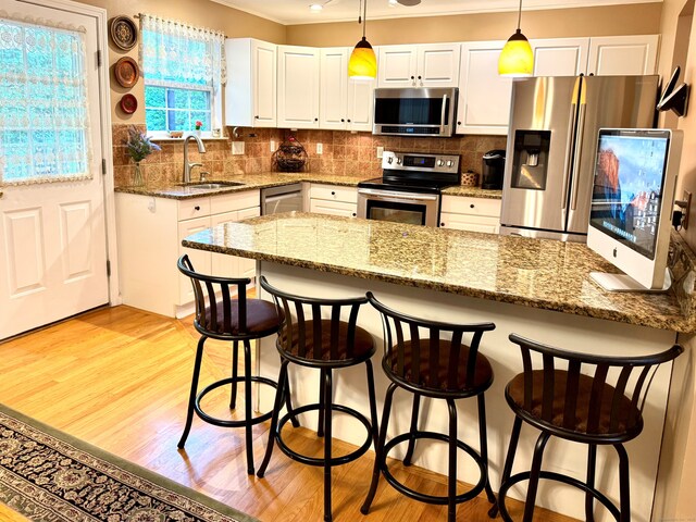 168 Cooper Ln, Hamden, CT 06514 - kitchen featuring appliances with stainless steel finishes, white cabinetry, light wood-style flooring, pendant lighting, and crown molding
