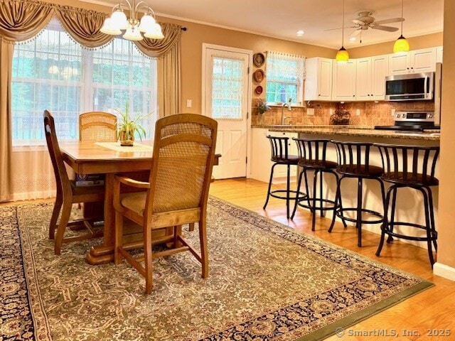 168 Cooper Ln, Hamden, CT 06514 - dining space with light wood finished floors, a chandelier, ornamental molding, and ceiling fan