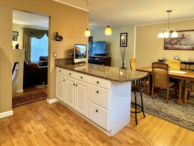 168 Cooper Ln, Hamden, CT 06514 - kitchen with a peninsula, light wood-style floors, white cabinetry, a breakfast bar, and ornamental molding