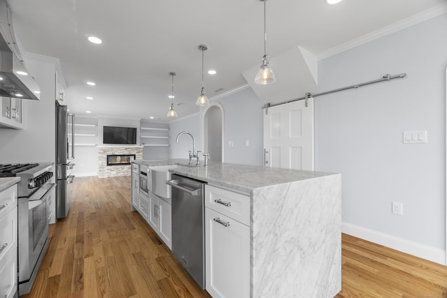 26 Meadowood Ln, Old Saybrook, CT 06475 - kitchen with stainless steel appliances, crown molding, open floor plan, white cabinets, and arched walkways