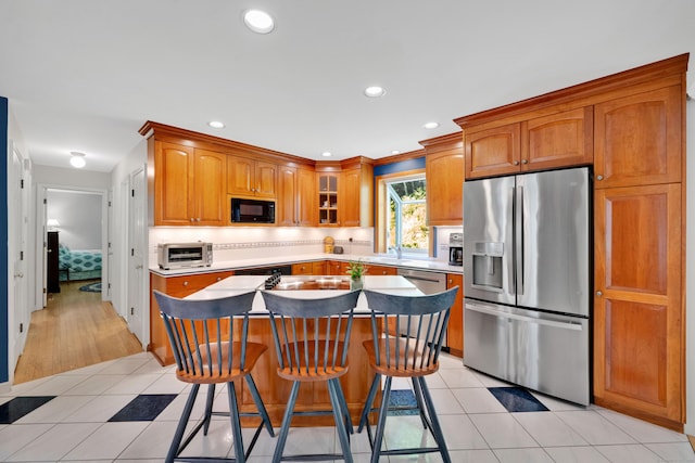 431 Fan Hill Rd, Monroe, CT 06468 - kitchen featuring appliances with stainless steel finishes, a kitchen island, a kitchen breakfast bar, decorative backsplash, and glass insert cabinets