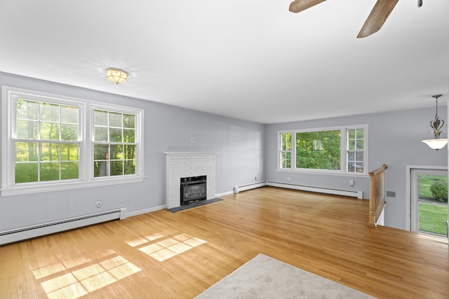 538 Quaddick Rd, Thompson, CT 06277 - unfurnished living room with light wood-type flooring, a baseboard radiator, and a brick fireplace