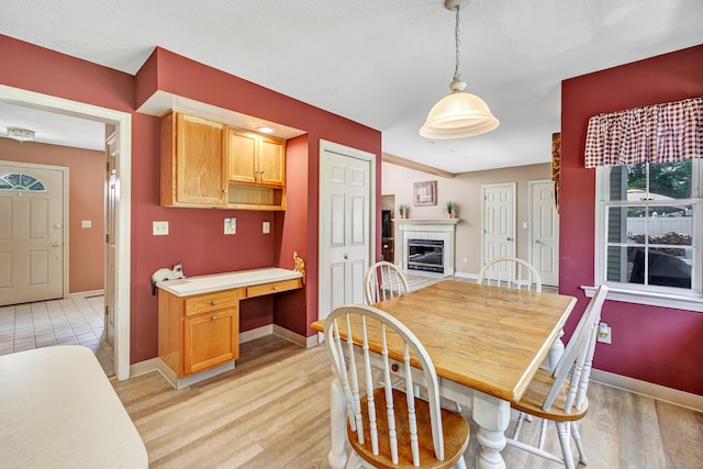 56 Stagecoach Cir, Milford, CT 06460 - dining room featuring light wood-style floors, a fireplace, and built in desk