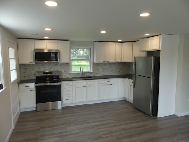 57 Pinehurst Ave, New Britain, CT 06053 - kitchen featuring appliances with stainless steel finishes, dark countertops, decorative backsplash, white cabinets, and recessed lighting