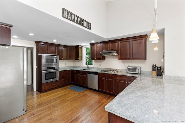141 Cannon St, Hamden, CT 06518 - kitchen with appliances with stainless steel finishes, under cabinet range hood, dark brown cabinets, light wood-style floors, and pendant lighting