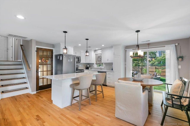 2 Sunwoods Cir, Hamden, CT 06518 - kitchen featuring appliances with stainless steel finishes, white cabinets, a chandelier, a kitchen island, and tasteful backsplash