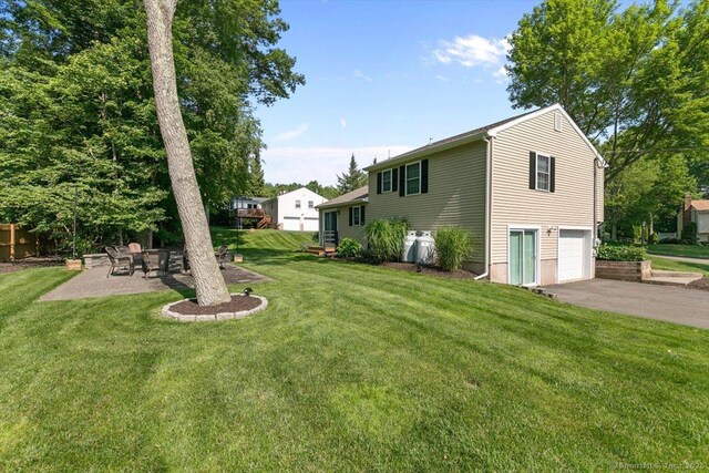 2 Sunwoods Cir, Hamden, CT 06518 - view of green lawn featuring driveway, a garage, and a patio