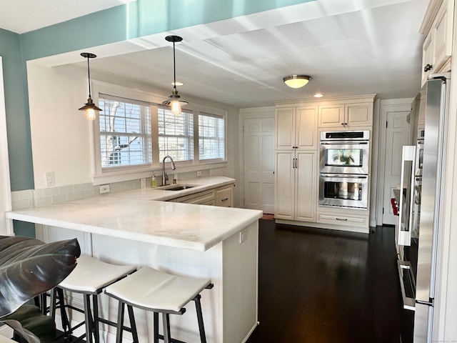 111 Spring Garden St, Hamden, CT 06517 - kitchen featuring appliances with stainless steel finishes, a peninsula, light countertops, a kitchen bar, and recessed lighting