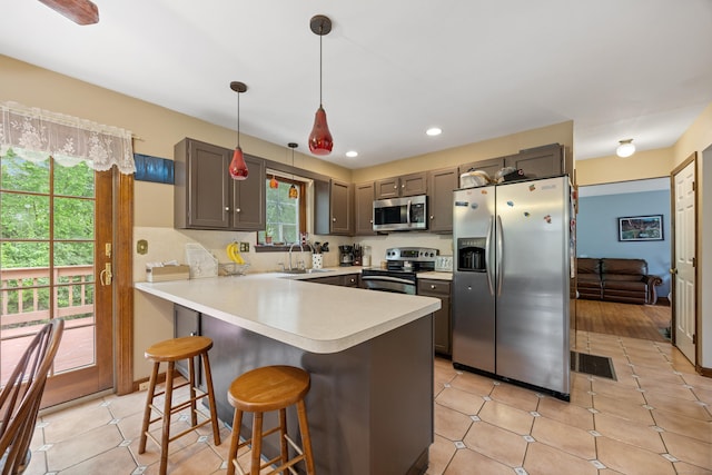 291 Guinevere Rdg, Cheshire, CT 06410 - kitchen with stainless steel appliances, a peninsula, a kitchen bar, light countertops, and hanging light fixtures