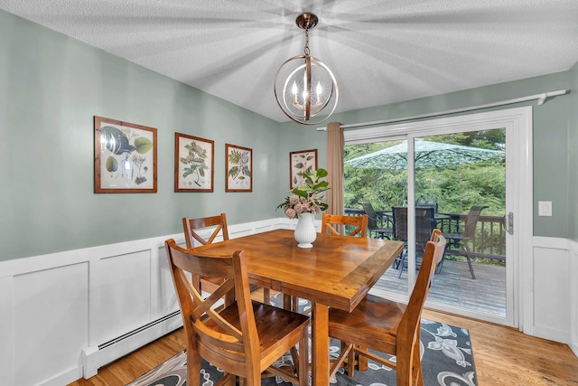 81 Charter Oak Dr, East Lyme, CT 06333 - dining space with baseboard heating, a chandelier, a wainscoted wall, light wood-style flooring, and a decorative wall