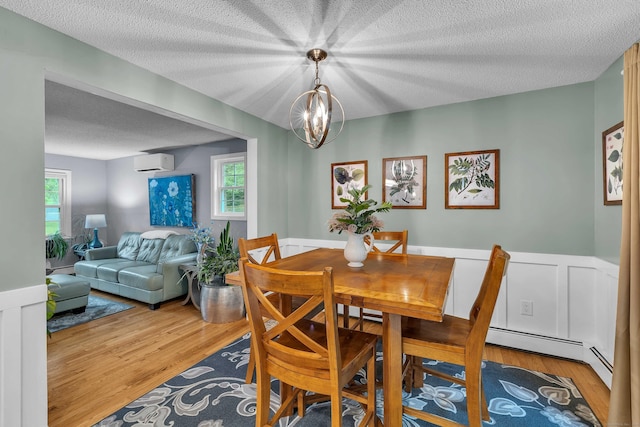 81 Charter Oak Dr, East Lyme, CT 06333 - dining room featuring wainscoting, wood finished floors, a textured ceiling, a chandelier, and an AC wall unit