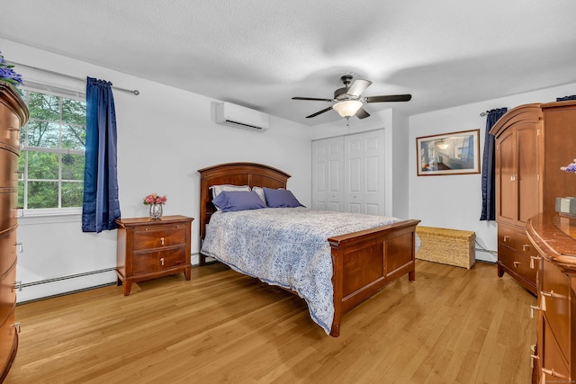 81 Charter Oak Dr, East Lyme, CT 06333 - bedroom featuring baseboard heating, a wall mounted AC, light wood-style floors, a closet, and a textured ceiling
