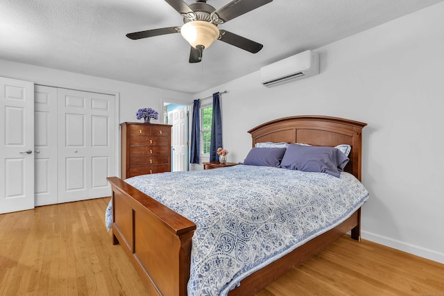 81 Charter Oak Dr, East Lyme, CT 06333 - bedroom featuring an AC wall unit, light wood-style floors, a closet, ceiling fan, and a textured ceiling