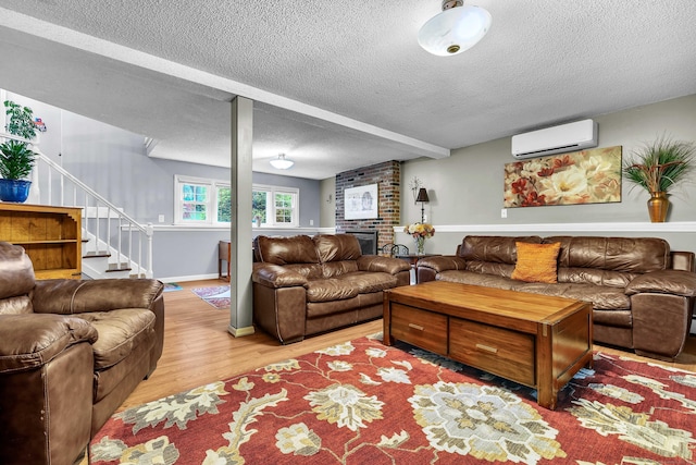 81 Charter Oak Dr, East Lyme, CT 06333 - living area with a wall unit AC, a textured ceiling, light wood-type flooring, stairs, and a brick fireplace
