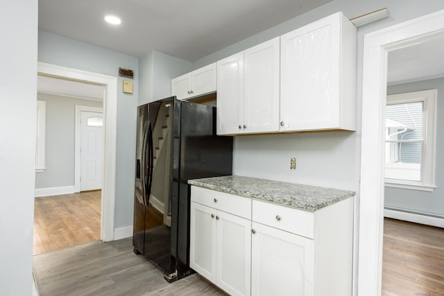 49 Olmsted St, East Hartford, CT 06108 - kitchen with black fridge with ice dispenser, light wood-style floors, white cabinets, baseboard heating, and light stone counters