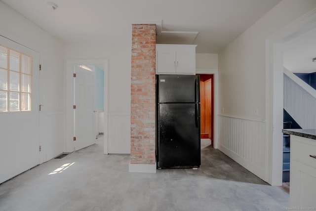 103 Clay St, Thomaston, CT 06787 - kitchen with freestanding refrigerator, finished concrete flooring, white cabinets, and a wainscoted wall