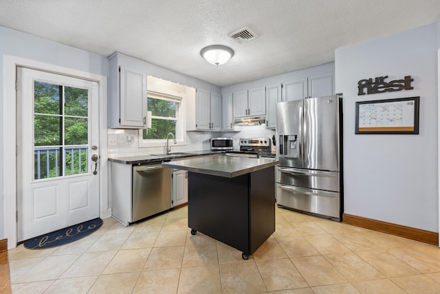 489 Thomaston Rd, Watertown, CT 06795 - kitchen with appliances with stainless steel finishes, under cabinet range hood, dark countertops, tasteful backsplash, and a kitchen island