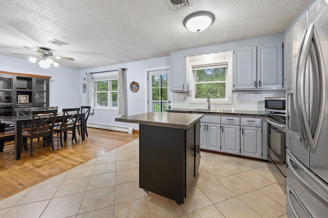 489 Thomaston Rd, Watertown, CT 06795 - kitchen with appliances with stainless steel finishes, dark countertops, a baseboard heating unit, gray cabinetry, and a center island