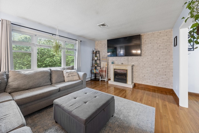 489 Thomaston Rd, Watertown, CT 06795 - living room with a textured ceiling, wood finished floors, a brick fireplace, and baseboard heating