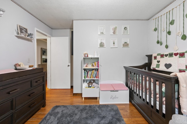 489 Thomaston Rd, Watertown, CT 06795 - bedroom with light wood finished floors, a textured ceiling, and a crib