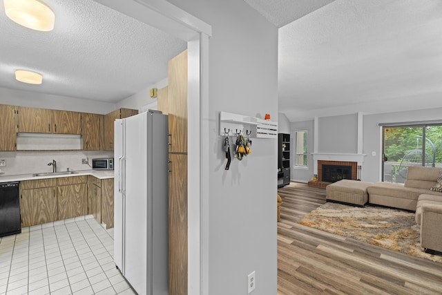 21 Heritage Cir Unit A, Southbury, CT 06488 - kitchen with freestanding refrigerator, a textured ceiling, light countertops, open floor plan, and brown cabinetry