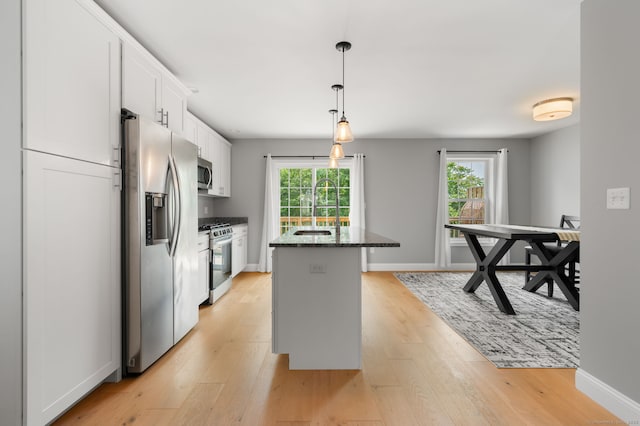 64 Scotch Cap Rd Unit 173, Waterford, CT 06375 - kitchen featuring appliances with stainless steel finishes, white cabinets, light wood-style floors, a kitchen island with sink, and decorative light fixtures