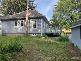 1063 N Main St, Killingly, CT 06241 - view of side of home with a wooden deck, a lawn, and a chimney