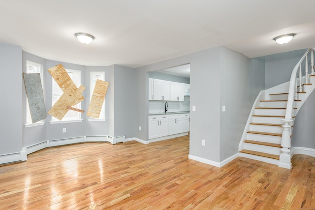 68 School St, Hartford, CT 06106 - unfurnished living room featuring light wood-style flooring, stairway, and a baseboard heating unit