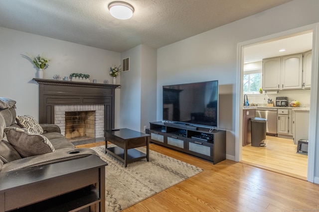 263 New Britain Ave, Newington, CT 06111 - living room featuring light wood-style floors, a brick fireplace, and a textured ceiling