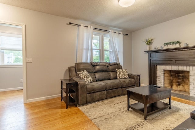 263 New Britain Ave, Newington, CT 06111 - living room featuring plenty of natural light, light wood-style flooring, a textured ceiling, and a fireplace