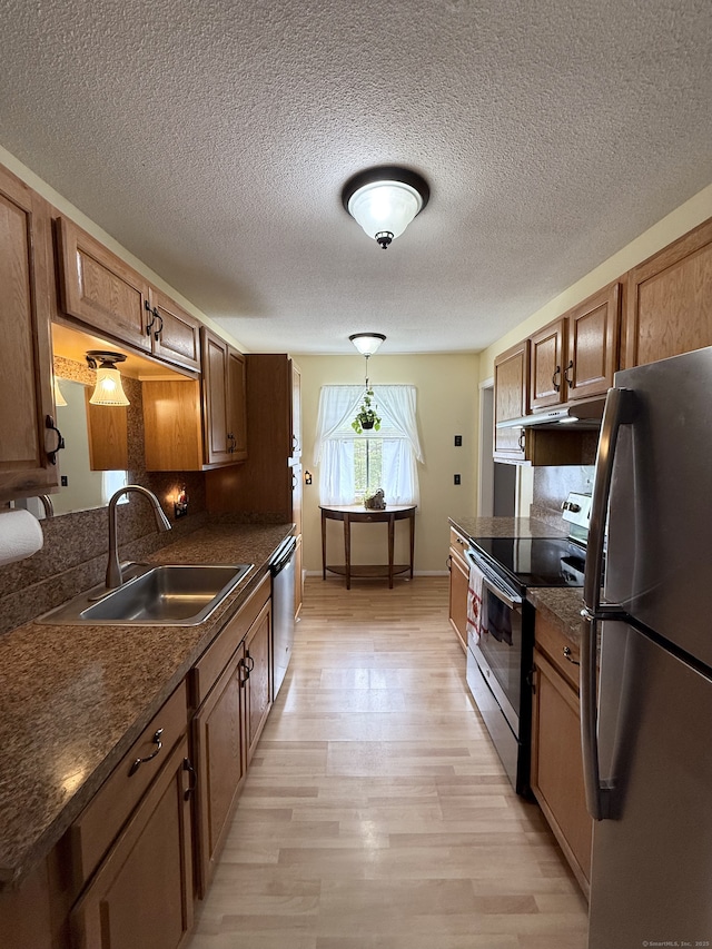 13 Heritage Vlg Unit E, Southbury, CT 06488 - kitchen with stainless steel appliances, dark countertops, light wood finished floors, a textured ceiling, and brown cabinetry