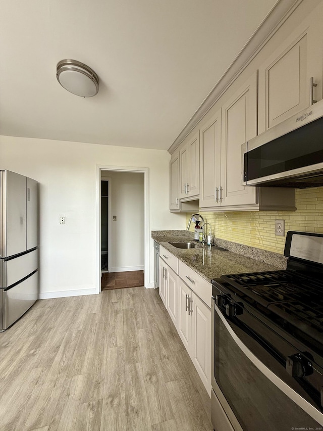1 Strawberry Hill Ct Apt 2D, Stamford, CT 06902 - kitchen with stainless steel appliances, backsplash, dark stone counters, and light wood finished floors