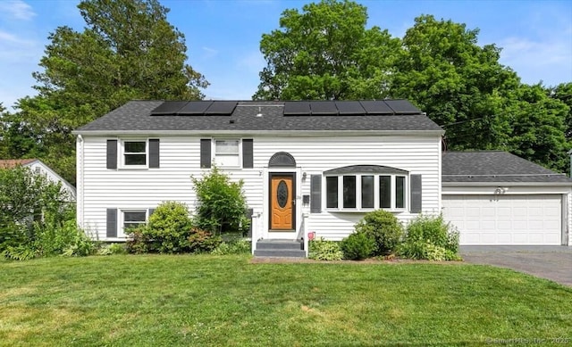 29 Pembroke Rd, Hamden, CT 06514 - view of front of home with asphalt driveway, a front yard, solar panels, an attached garage, and a shingled roof