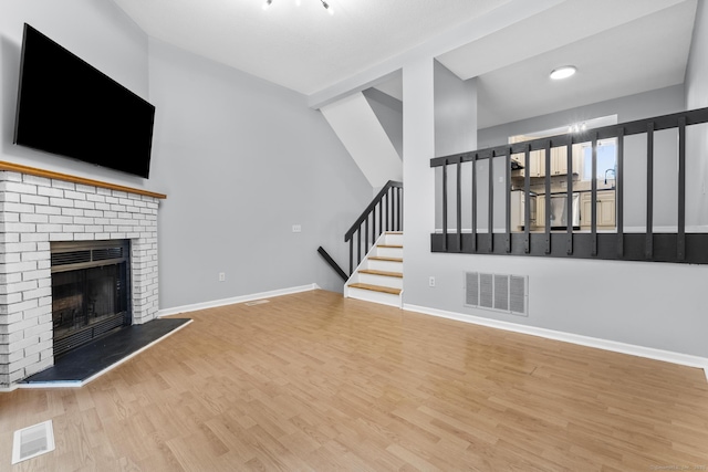 410 Farmington Ave Apt M2, New Britain, CT 06053 - unfurnished living room with wood finished floors, stairs, and a brick fireplace