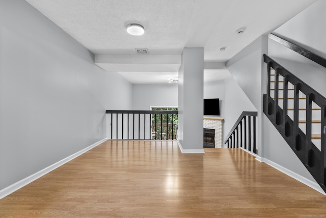 410 Farmington Ave Apt M2, New Britain, CT 06053 - unfurnished living room with wood finished floors, a fireplace, and a textured ceiling