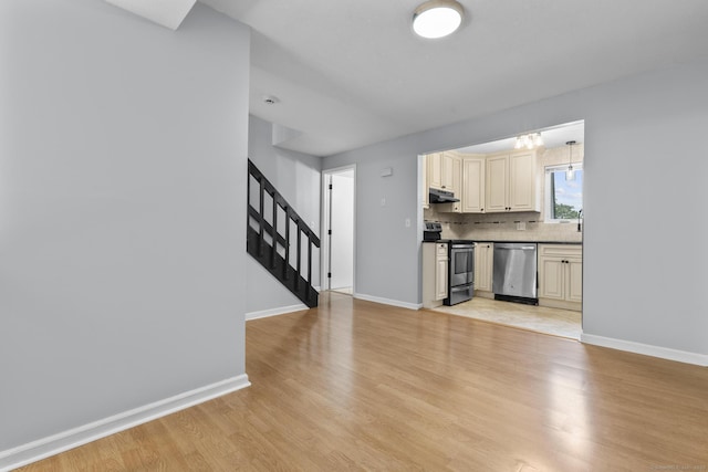 410 Farmington Ave Apt M2, New Britain, CT 06053 - kitchen with appliances with stainless steel finishes, under cabinet range hood, cream cabinetry, light wood-style floors, and decorative backsplash