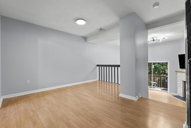410 Farmington Ave Apt M2, New Britain, CT 06053 - empty room with light wood finished floors, a textured ceiling, a fireplace, and a smoke detector