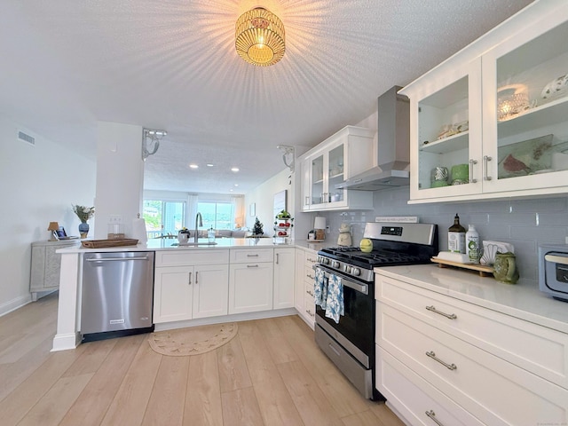 5 Mansfield Grove Rd Apt 146, East Haven, CT 06512 - kitchen with wall chimney range hood, appliances with stainless steel finishes, a peninsula, tasteful backsplash, and white cabinets