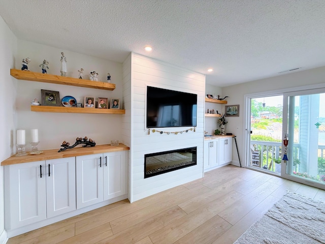 5 Mansfield Grove Rd Apt 146, East Haven, CT 06512 - unfurnished living room with light wood-type flooring, a textured ceiling, a large fireplace, and recessed lighting
