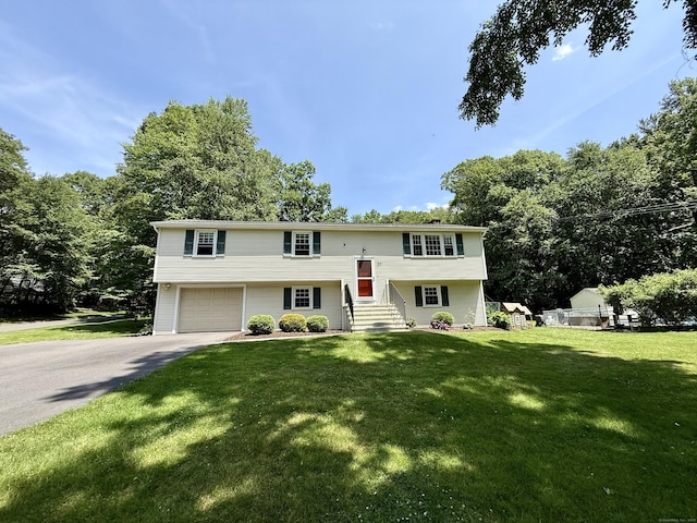 37 Pine Hill Rd, Tolland, CT 06084 - split foyer home with asphalt driveway, a garage, a front lawn, and view of wooded area