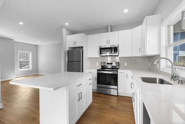 195 Arctic St, Bridgeport, CT 06608 - kitchen featuring appliances with stainless steel finishes, decorative backsplash, dark wood-type flooring, a kitchen island, and white cabinets
