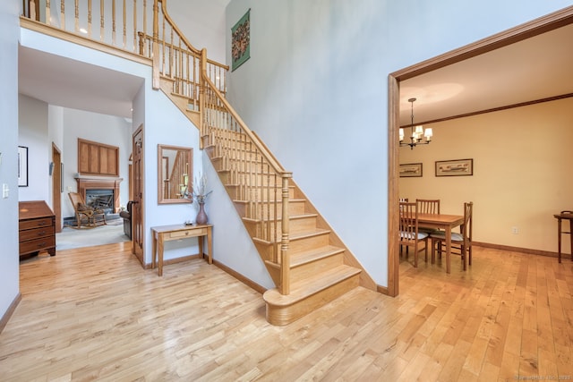 1047 Merrow Rd, Coventry, CT 06238 - stairs featuring wood-type flooring, a high ceiling, a chandelier, and a fireplace