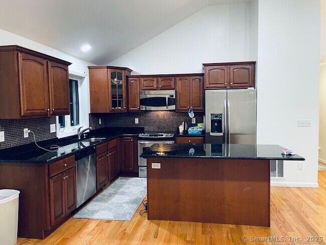 470 Nott St, Wethersfield, CT 06109 - kitchen with appliances with stainless steel finishes, vaulted ceiling, light wood finished floors, a kitchen island, and tasteful backsplash