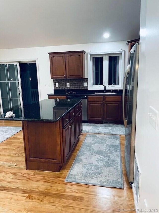 470 Nott St, Wethersfield, CT 06109 - kitchen with freestanding refrigerator, a center island, backsplash, light wood finished floors, and dark stone countertops
